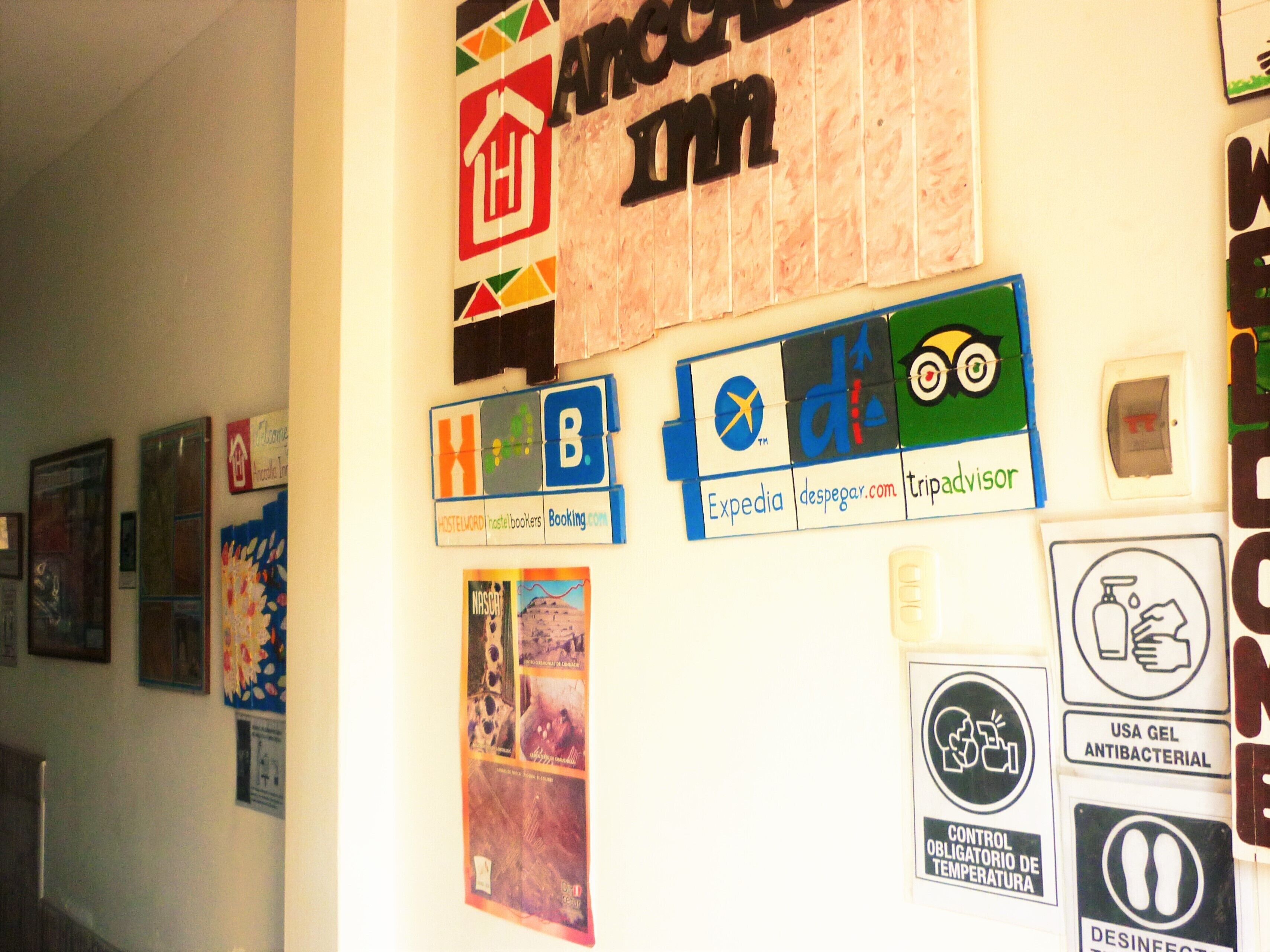 A wall with various signs and posters, including a sign for 'APACHE INN' and several travel-related logos like 'Expedia' and 'Booking.com'.