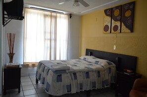 A bedroom with a bed, a ceiling fan, a TV, and artwork on the wall. - Hotel Gomez (Aguascalientes)