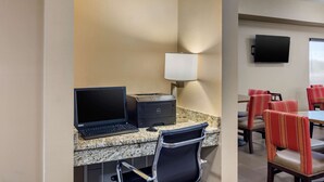 A hotel room with a desk, laptop, printer, and a TV on the wall. There are chairs and a table in the dining area. - Comfort Inn South Chesterfield - Colonial Heights (Colonial Heights)