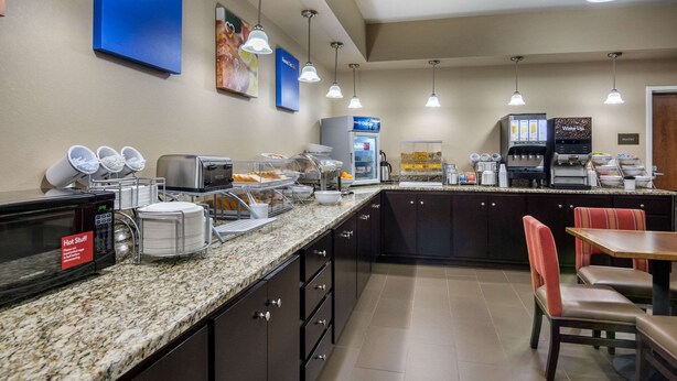 A hotel breakfast area with a self-service counter, microwave, coffee machines, and seating. - Comfort Inn South Chesterfield - Colonial Heights (Colonial Heights)