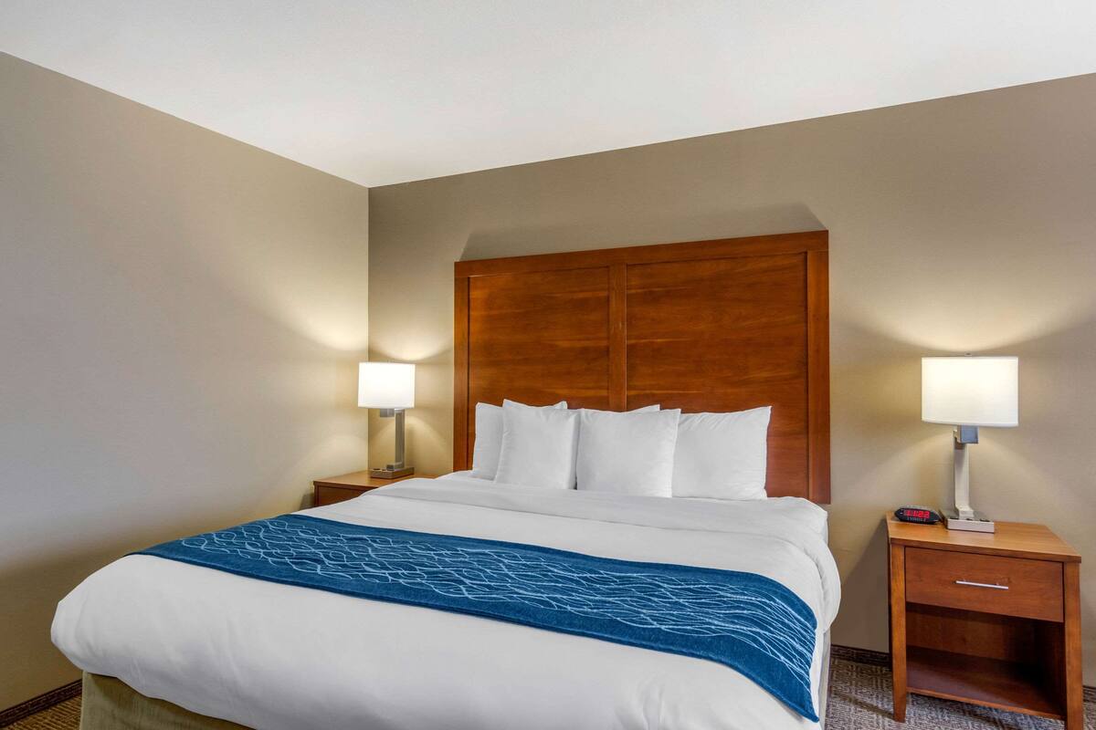 A hotel room with a large bed, two bedside tables with lamps, and a wooden headboard.
