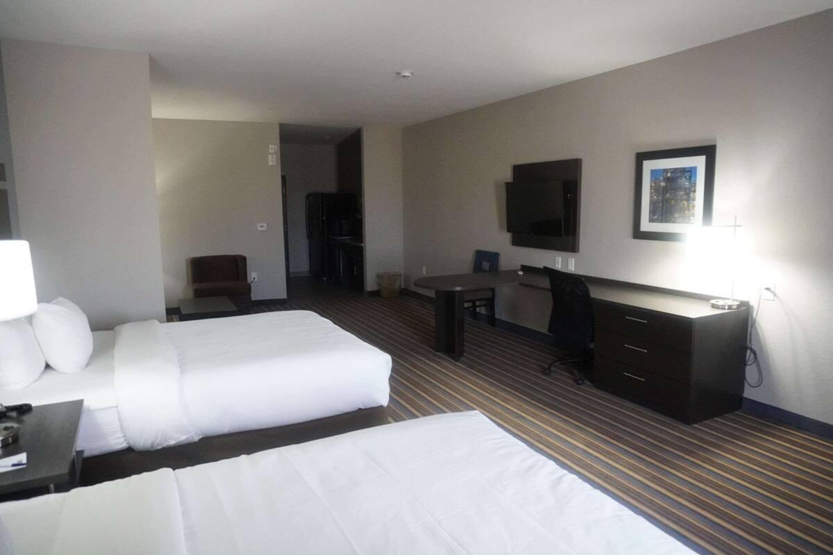 Habitación de hotel con dos camas, un escritorio, una silla, un televisor y un minibar.