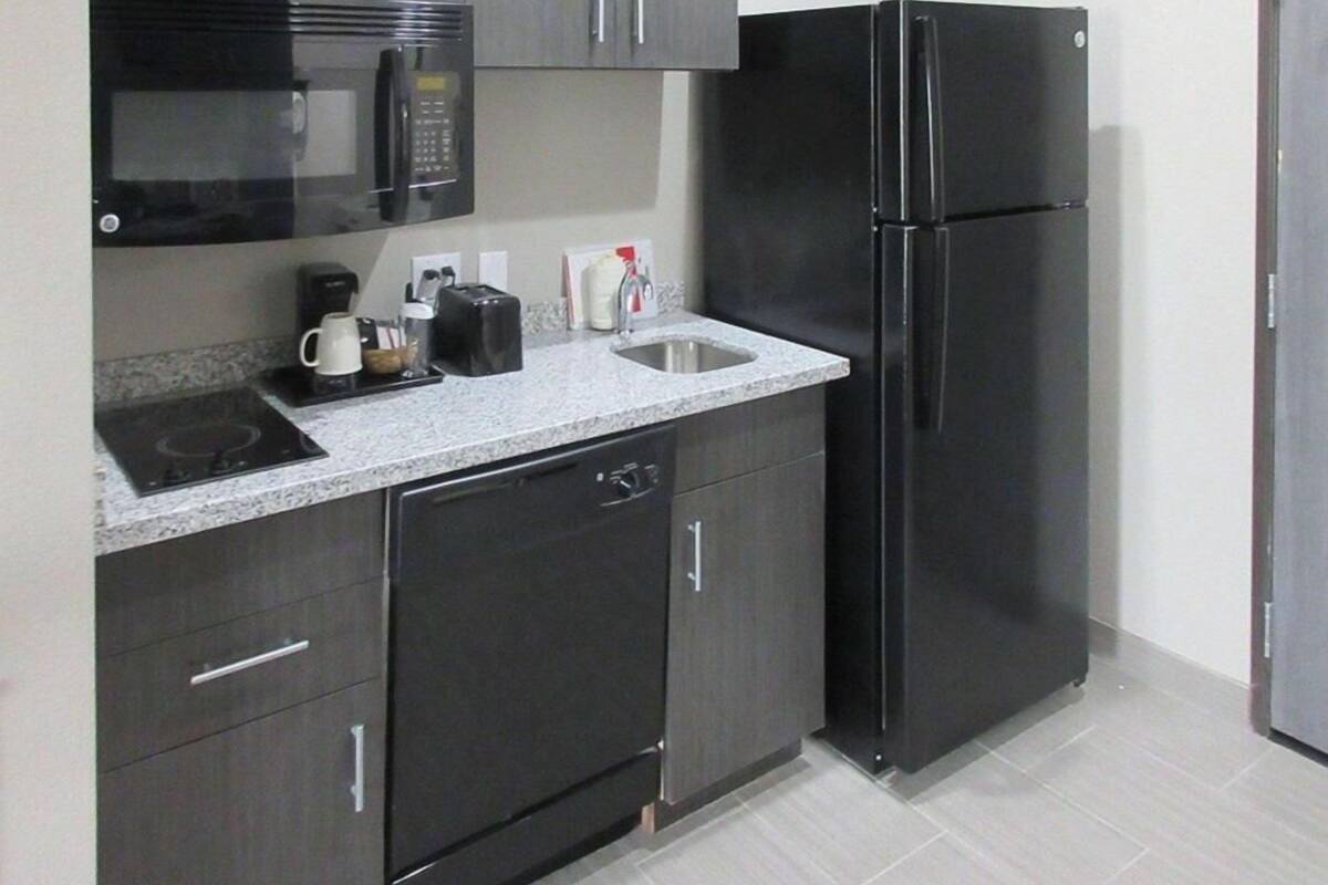 Cocina compacta con microondas, tostadora, lavabo y refrigerador negro.