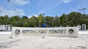 A sign for Moonlight Resort with a clear sky and trees in the background. - Moonlight Resort Koh Rongsanloem (Koh Rong Sanloem)