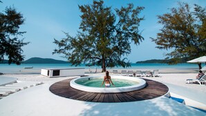 A circular pool with a wooden deck, surrounded by beach chairs and a lounge area, overlooking a beach and clear blue waters. - Moonlight Resort Koh Rongsanloem (Koh Rong Sanloem)