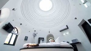 A circular ceiling with a central skylight, a bed with a white headboard, and a small window with a view of the sky. - Moonlight Resort Koh Rongsanloem (Koh Rong Sanloem)
