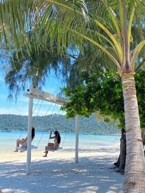 A beach with a swing set, palm trees, and a clear view of the water. - Moonlight Resort Koh Rongsanloem (Koh Rong Sanloem)