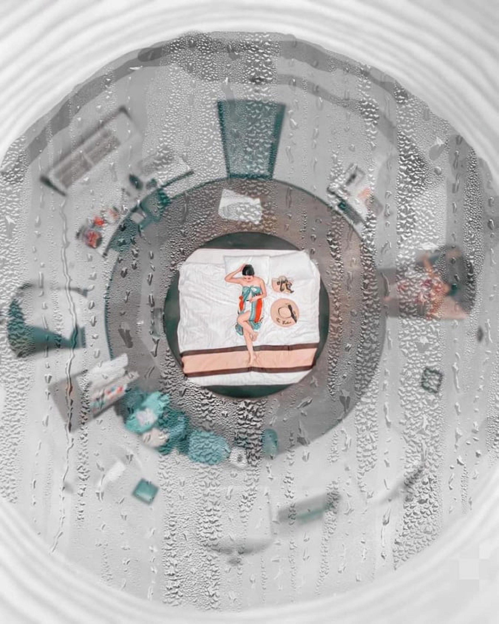 A circular room with a central bed, a circular window, and a patterned floor.