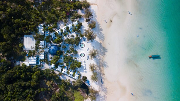 An aerial view of a beach resort with multiple dome-shaped structures, a sandy beach, and a few boats in the water. - Moonlight Resort Koh Rongsanloem (Koh Rong Sanloem)