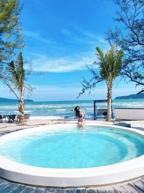 Une piscine où se trouve une personne, entourée de palmiers et offrant une vue sur l’océan.