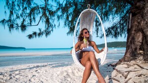 A person relaxing on a wicker swing chair by the beach. - Moonlight Resort Koh Rongsanloem (Koh Rong Sanloem)