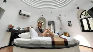 A circular room with a skylight, a bed, and a small table with items.