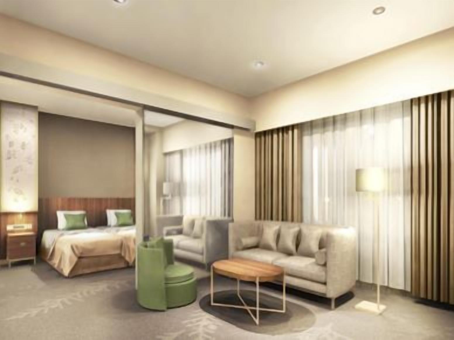 Ein modernes Hotelzimmer mit einem Bett, einer Couch, einem grünen Hocker und einer Stehlampe.