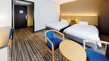 A hotel room with two beds, a small table, two chairs, and a patterned carpet.