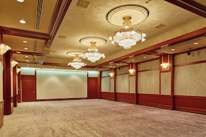 A large, well-lit conference room with multiple chandeliers, wooden paneling, and a carpeted floor. - Hotel Nikko Tachikawa Tokyo (Tachikawa)