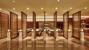 A spacious hotel lobby with a polished tile floor, wooden partitions, and a central seating area with tables and chairs. - Hotel Nikko Tachikawa Tokyo (Tachikawa)