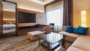 A modern hotel room with a sofa, a glass coffee table, a flat-screen TV, a desk, and a bed. - Hotel Nikko Tachikawa Tokyo (Tachikawa)