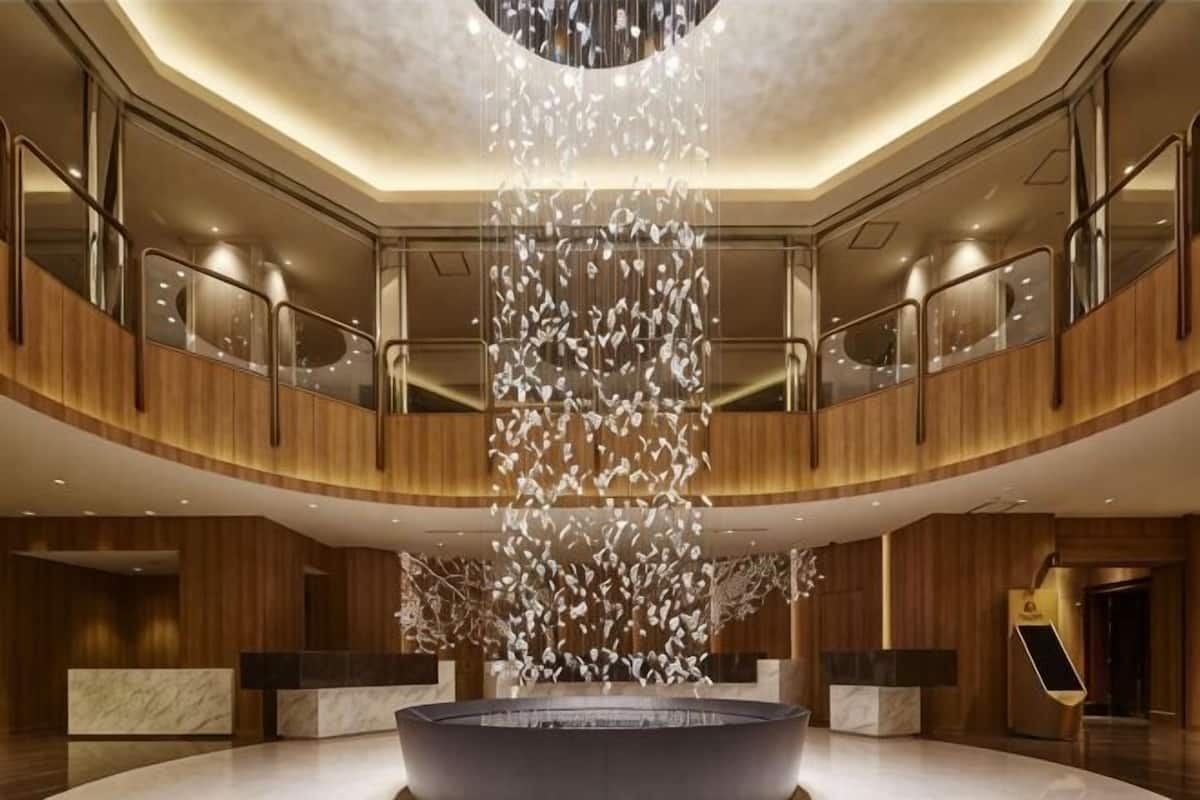 A spacious lobby with a central water feature, wooden paneling, and a modern reception desk.