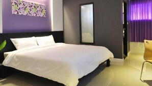 Une chambre d’hôtel moderne, dotée d’un grand lit, d’une table de chevet, d’un miroir et offrant une vue sur la ville par la fenêtre.