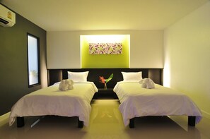 Ein Hotelzimmer mit zwei Einzelbetten, einem großen Fenster und einem an der Wand hängenden Kunstwerk.