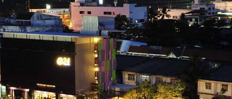 Un hotel con un llamativo letrero '024', una zona de estacionamiento y una entrada bien iluminada.