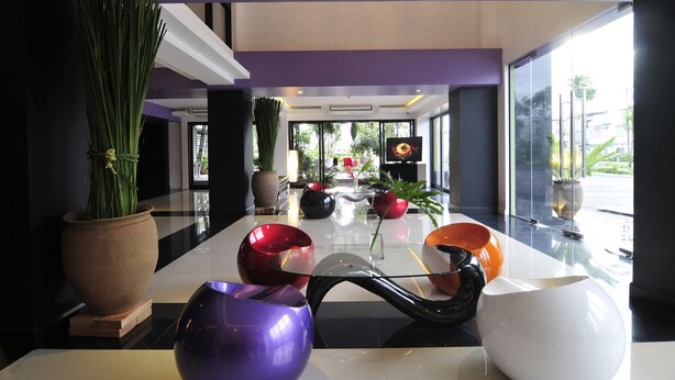 Un hall d’entrée moderne avec une table basse en verre, des plantes en pot et une grande fenêtre donnant sur l’extérieur.