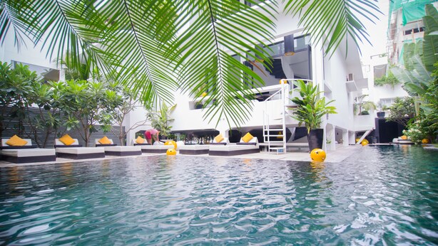 A pool area with lounge chairs and palm trees. - Arthur&Paul - Caters to Men (Phnom Penh)