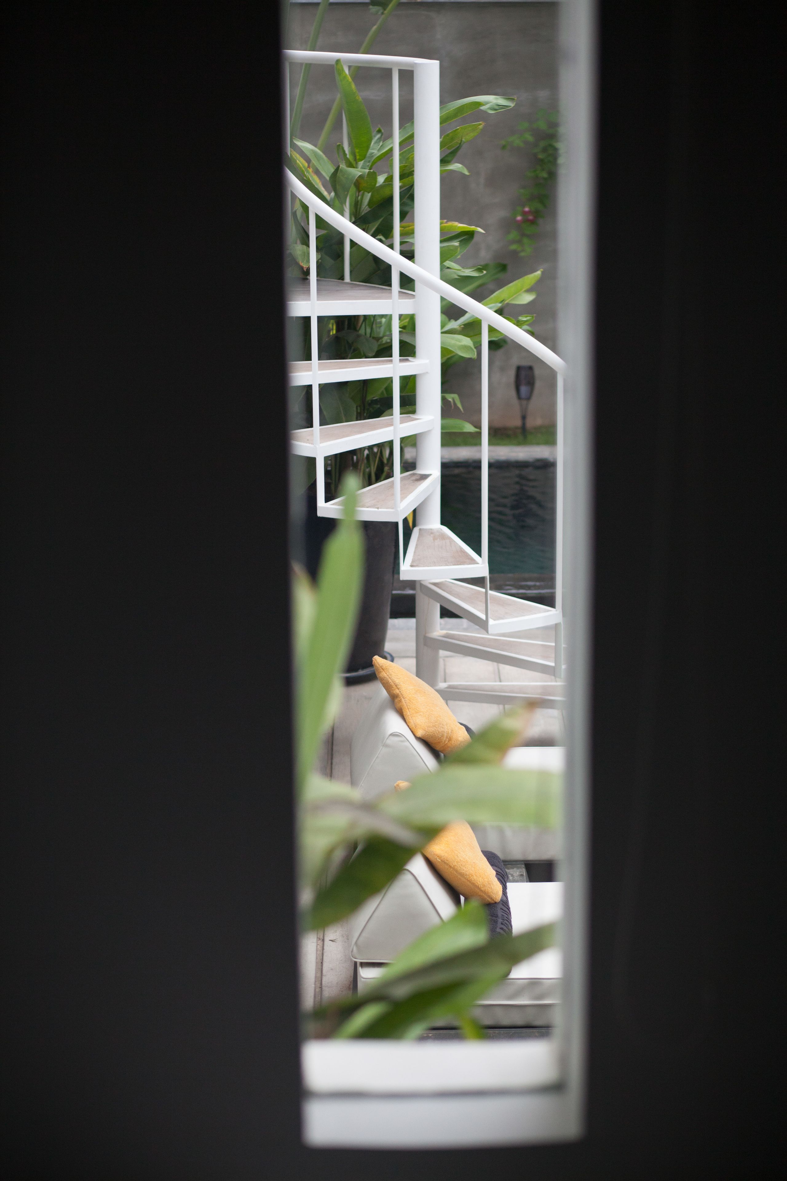Un intérieur moderne avec un escalier, un canapé et une vue sur un jardin.