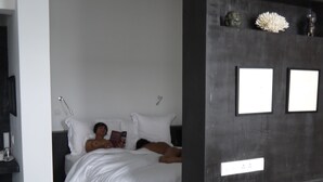 A modern bedroom with a bed, bedside tables, and a wall-mounted shelf with decorative items. - Arthur&Paul - Caters to Men (Phnom Penh)