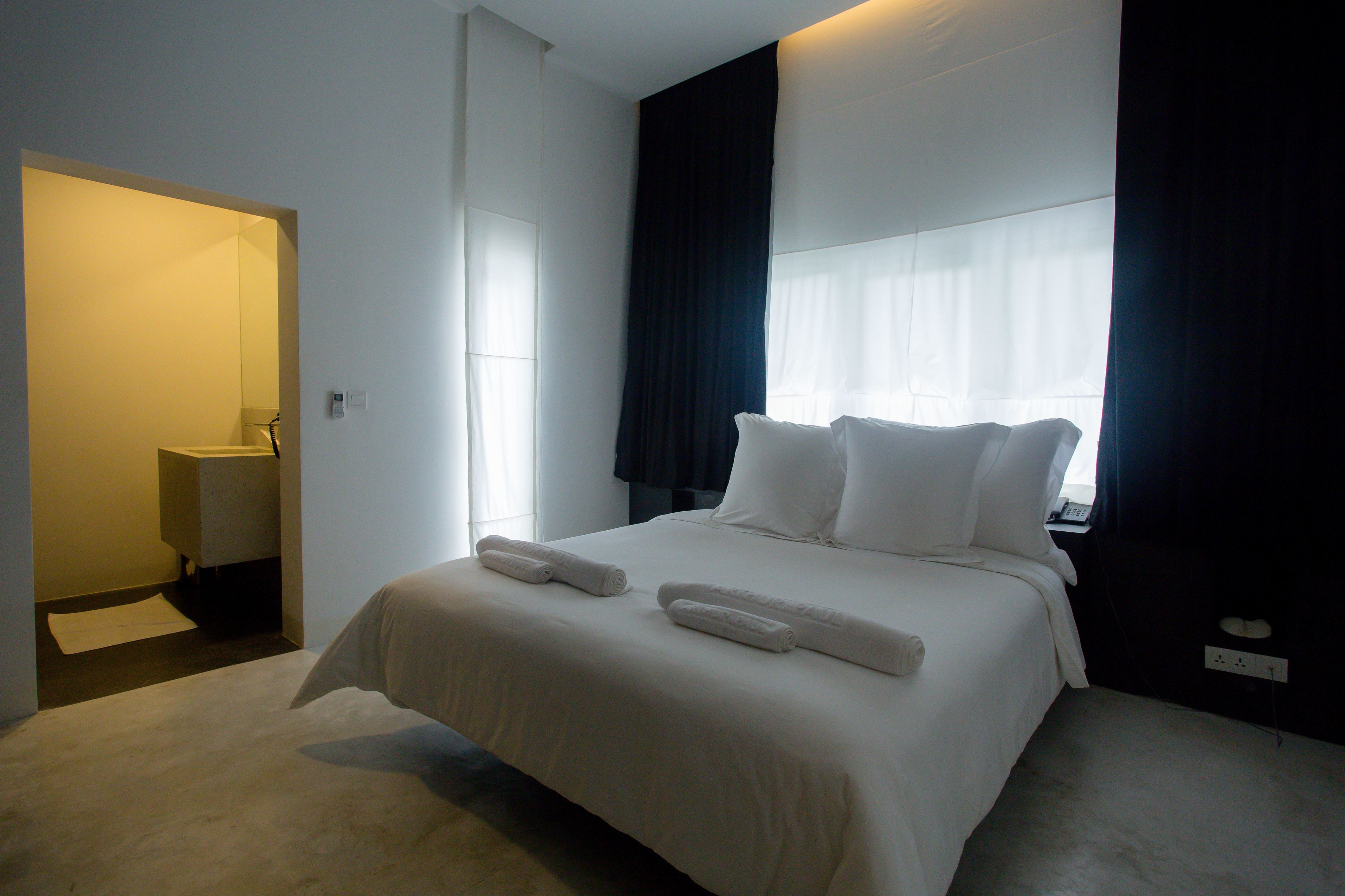 Een hotelkamer met een groot bed, twee kussens en twee opgerolde handdoeken.