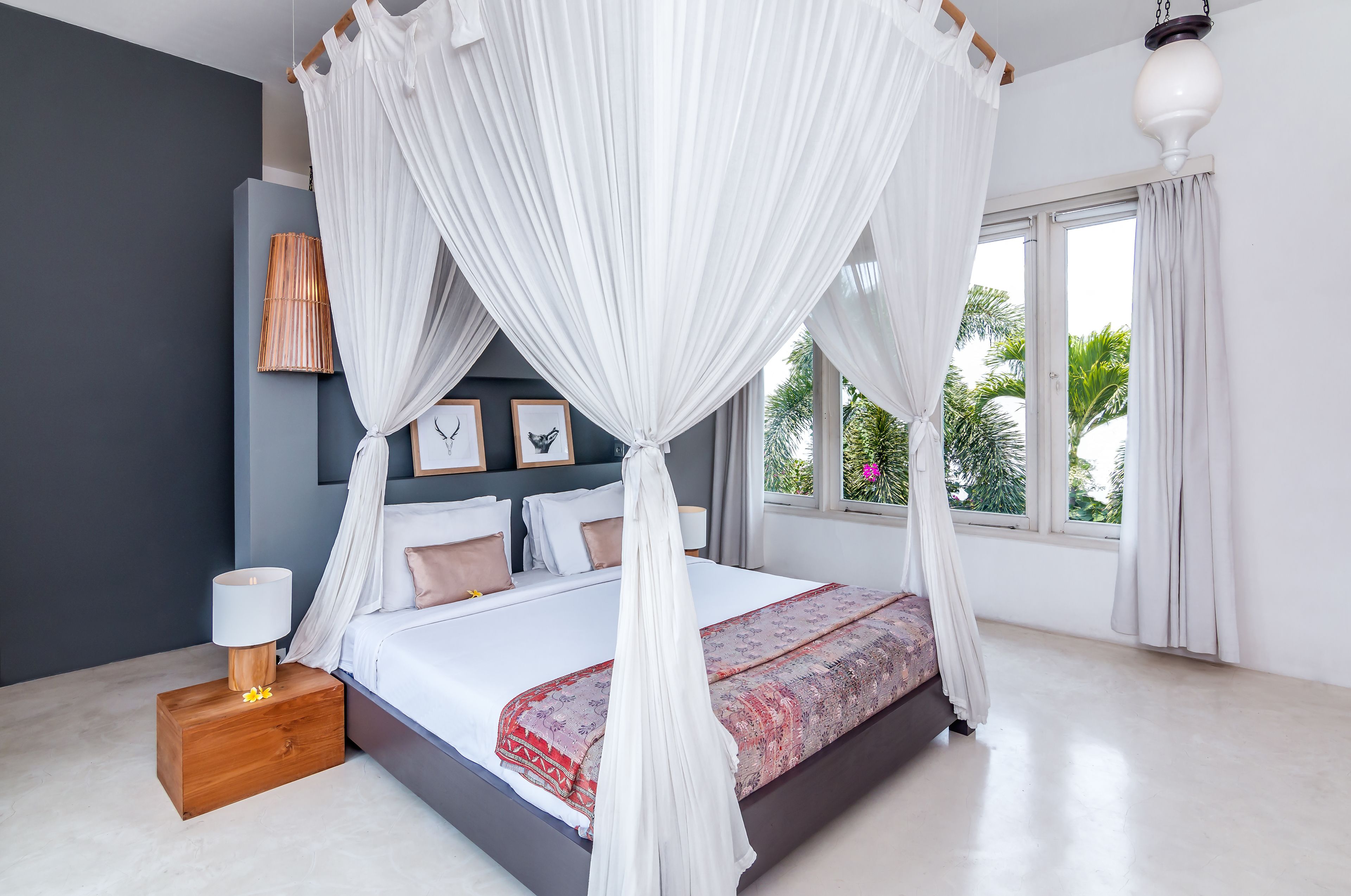 A bedroom with a bed, bedside table, lamp, and curtains.