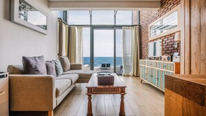 A living room with a sofa, a coffee table, and a view of the sea through large windows. - Zen Hideaway@Jeju (Seogwipo)