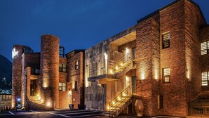 A modern building with brick walls, large cylindrical structures, and a staircase leading to an upper level. - Zen Hideaway@Jeju (Seogwipo)