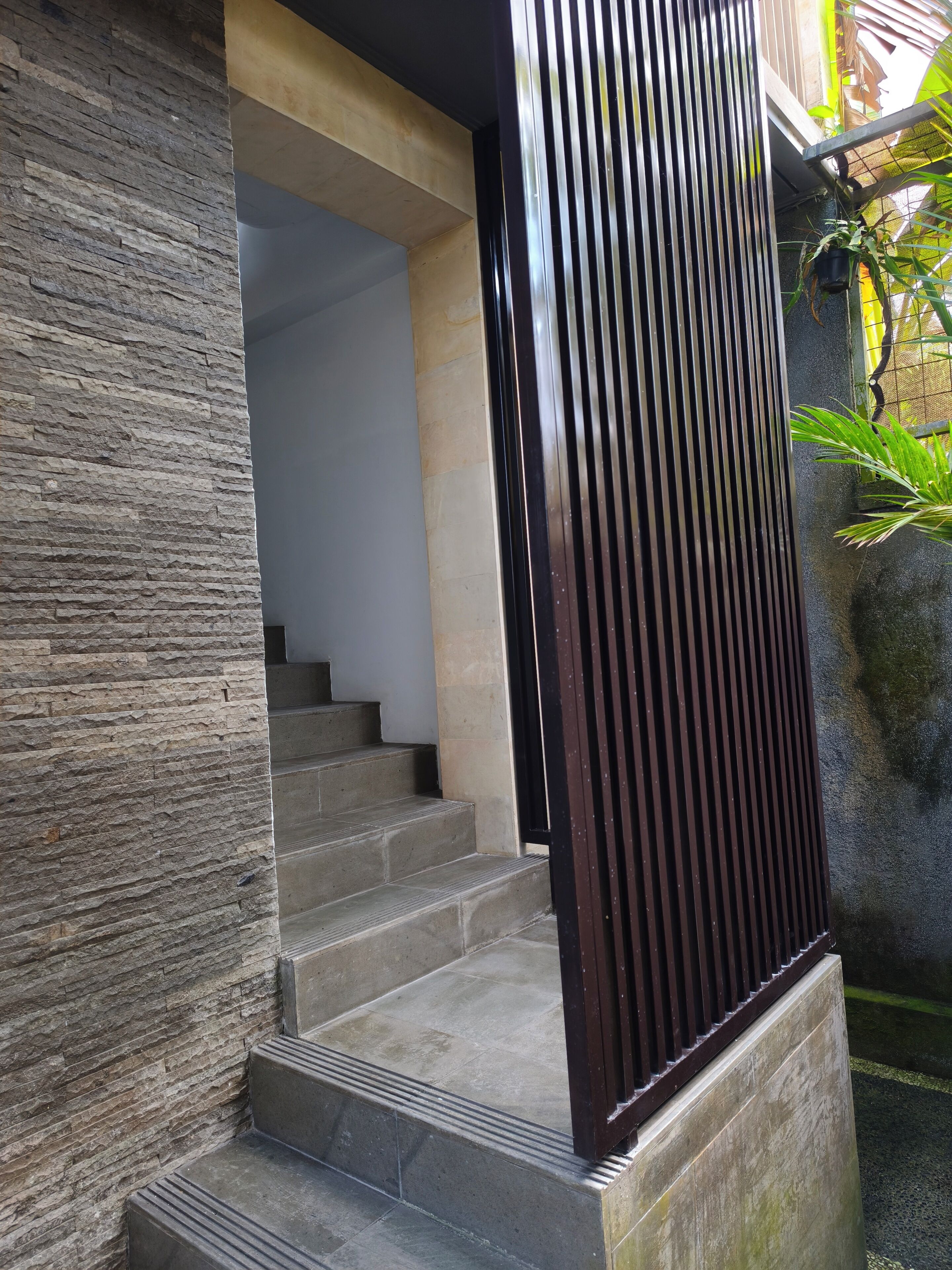 A staircase leading to an interior space, a stone wall, and a metal fence.