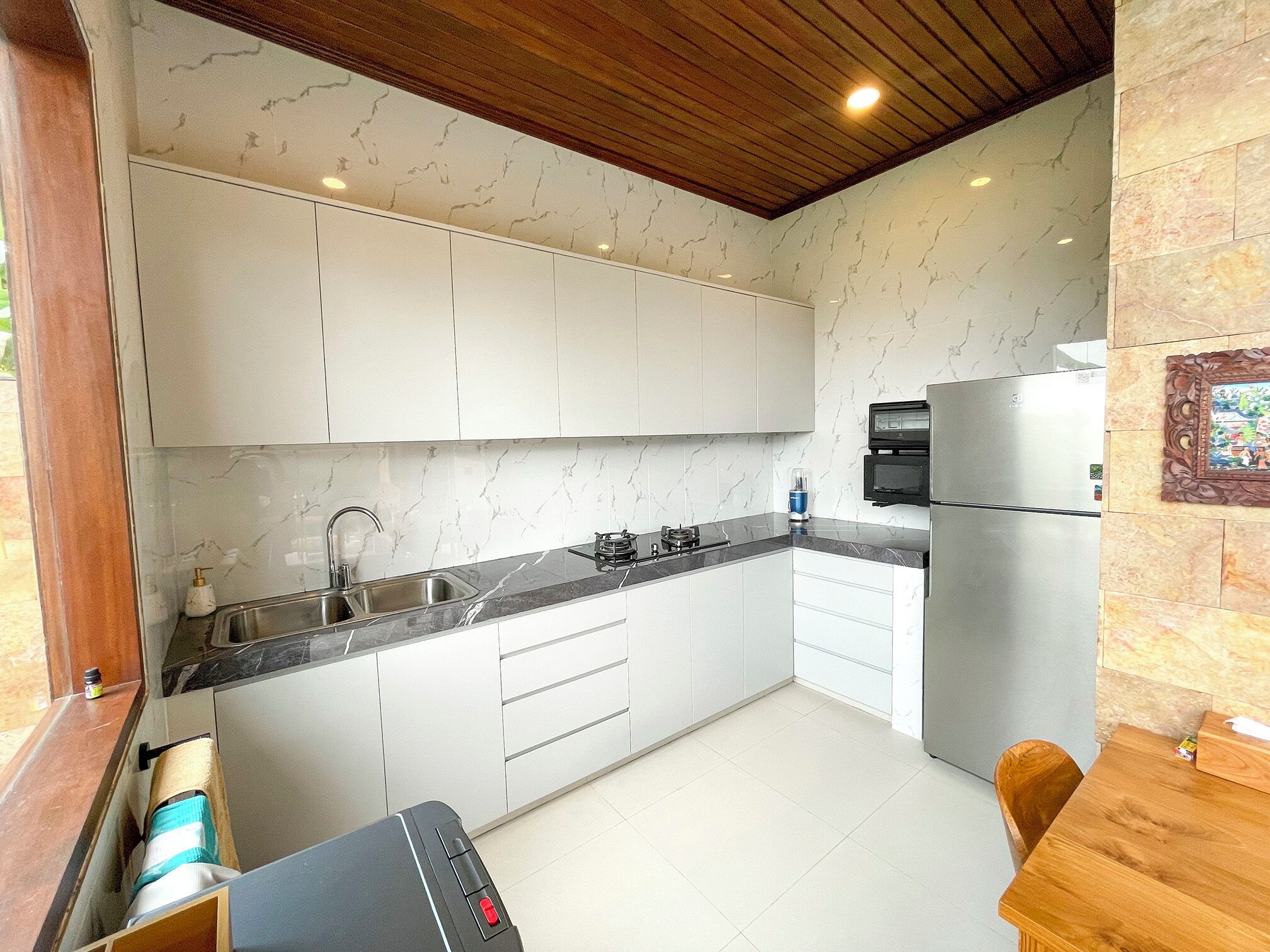A modern kitchen with white cabinets, a marble backsplash, and a built-in oven.