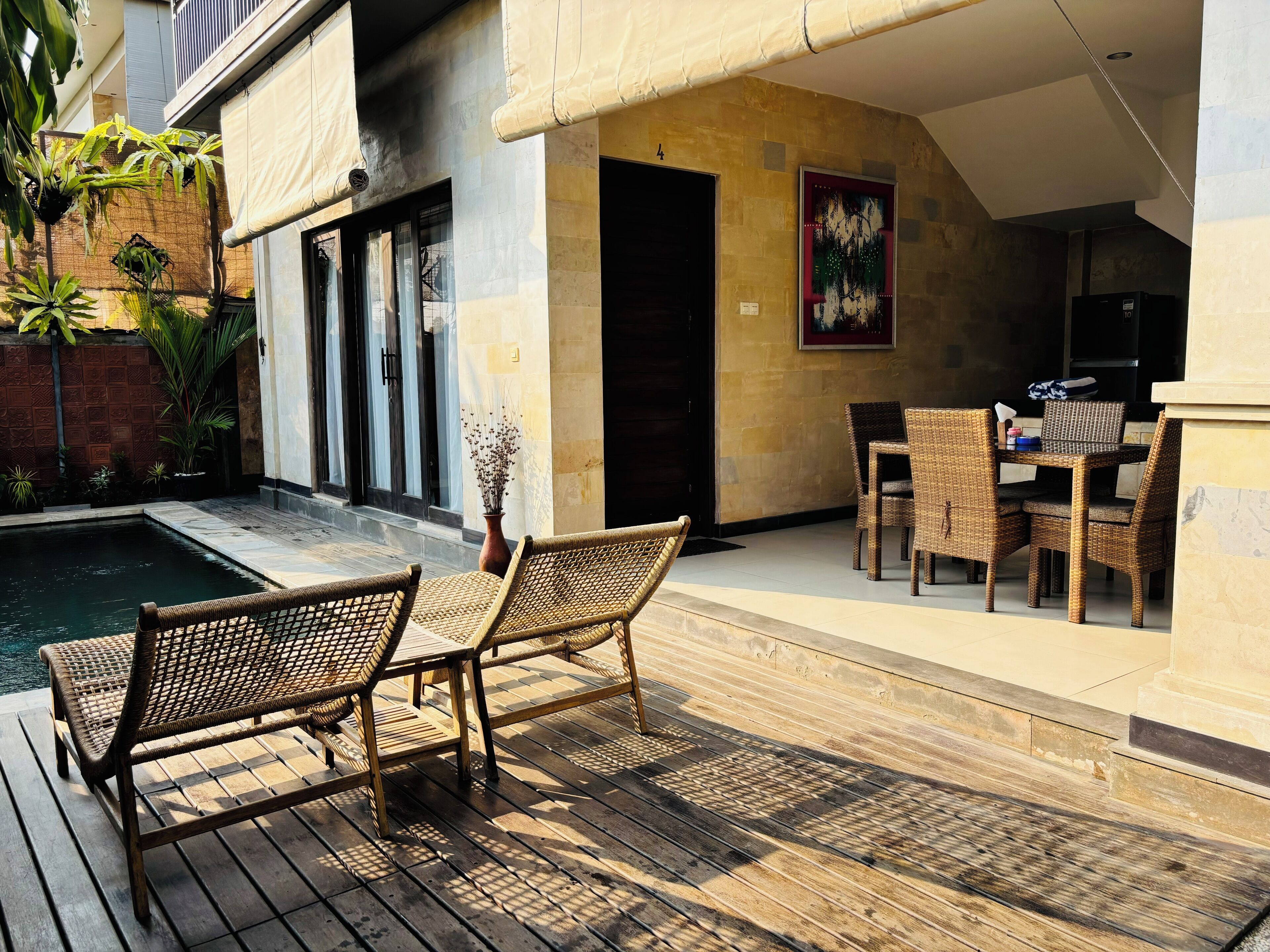 A wooden deck with wicker furniture, a pool, and a building with a stone facade.