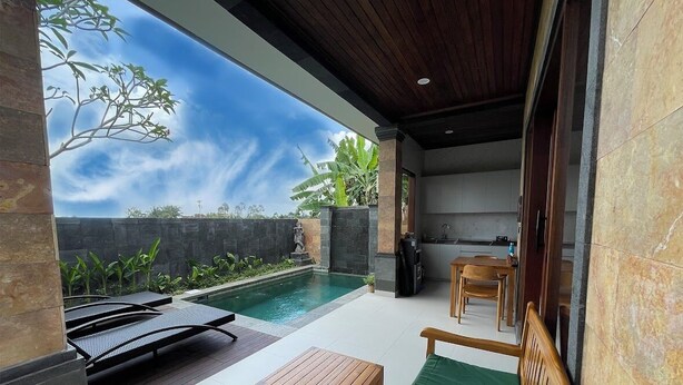 A modern outdoor patio with a pool, wooden furniture, and a kitchen area. - Uma Padi Villa (Ubud)