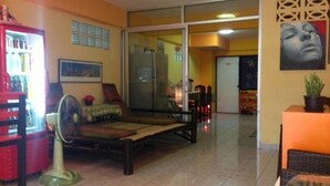 A room with a bed, a fan, a refrigerator, and a television. - Just Chill Inn - Hostel (Chiang Mai)