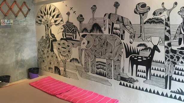A room with a large black and white mural depicting various animals and abstract patterns. There is a red striped towel on the floor. - Just Chill Inn - Hostel (Chiang Mai)