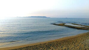 A beach with clear water, a sandy shore, and distant landforms. - Marilisa Hotel (Hersonissos)