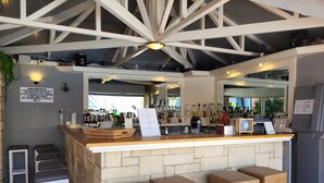 A bar area with a stone counter, four stools, and a variety of bottles and glasses. - Marilisa Hotel (Hersonissos)