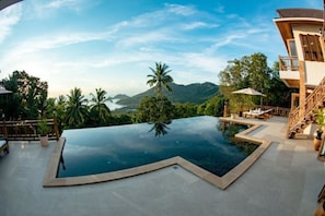 Una piscina infinita con vistas a montañas y palmeras.