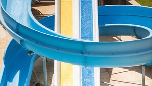 A water slide with a person at the top, a pool at the bottom, and a tiled deck area. - L'Oceanica Beach Resort Hotel - All Inclusive (Kemer)