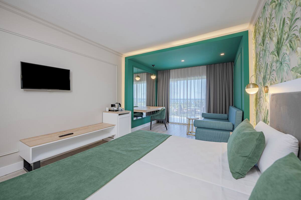 A modern hotel room with a bed, a desk, a chair, and a TV.
