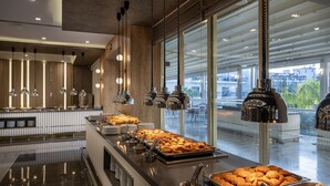 A buffet area with various food items, hanging pendant lights, and a view of the outdoors through large windows. - L'Oceanica Beach Resort Hotel - All Inclusive (Kemer)