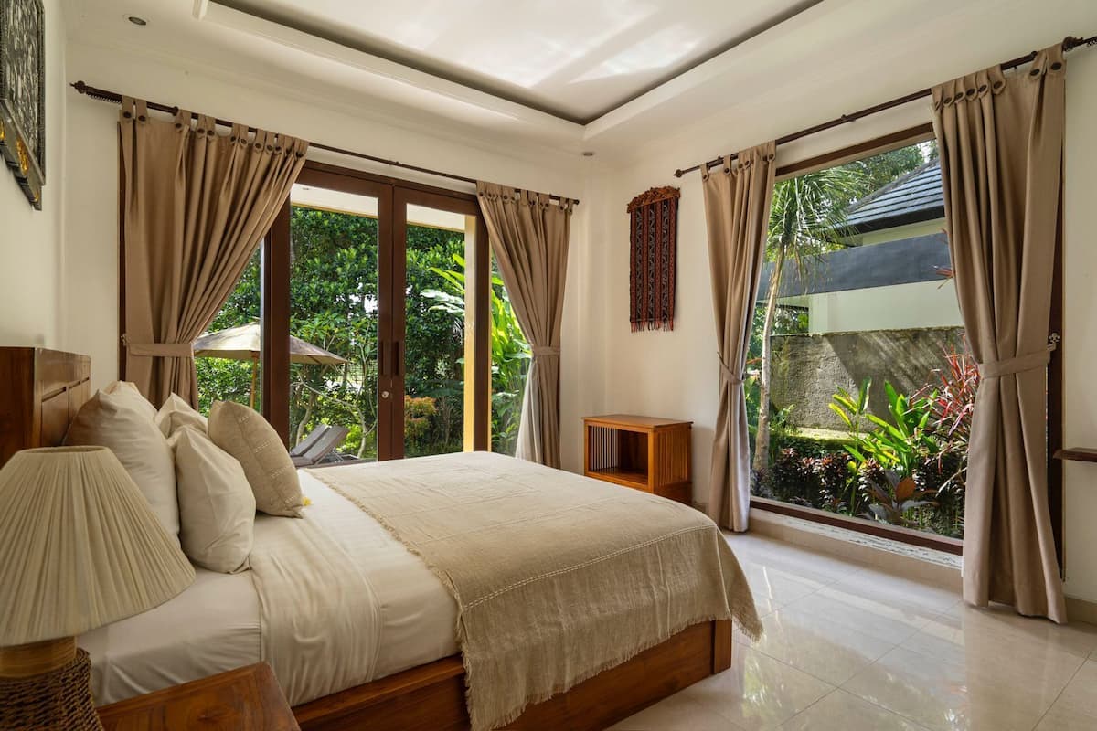 A bedroom with a bed, a nightstand, and a window with curtains.