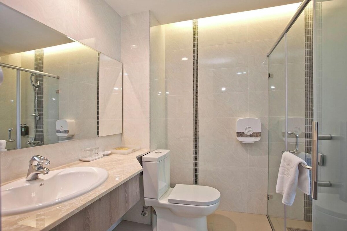 Un baño moderno con lavamanos, inodoro y ducha con mampara de vidrio.