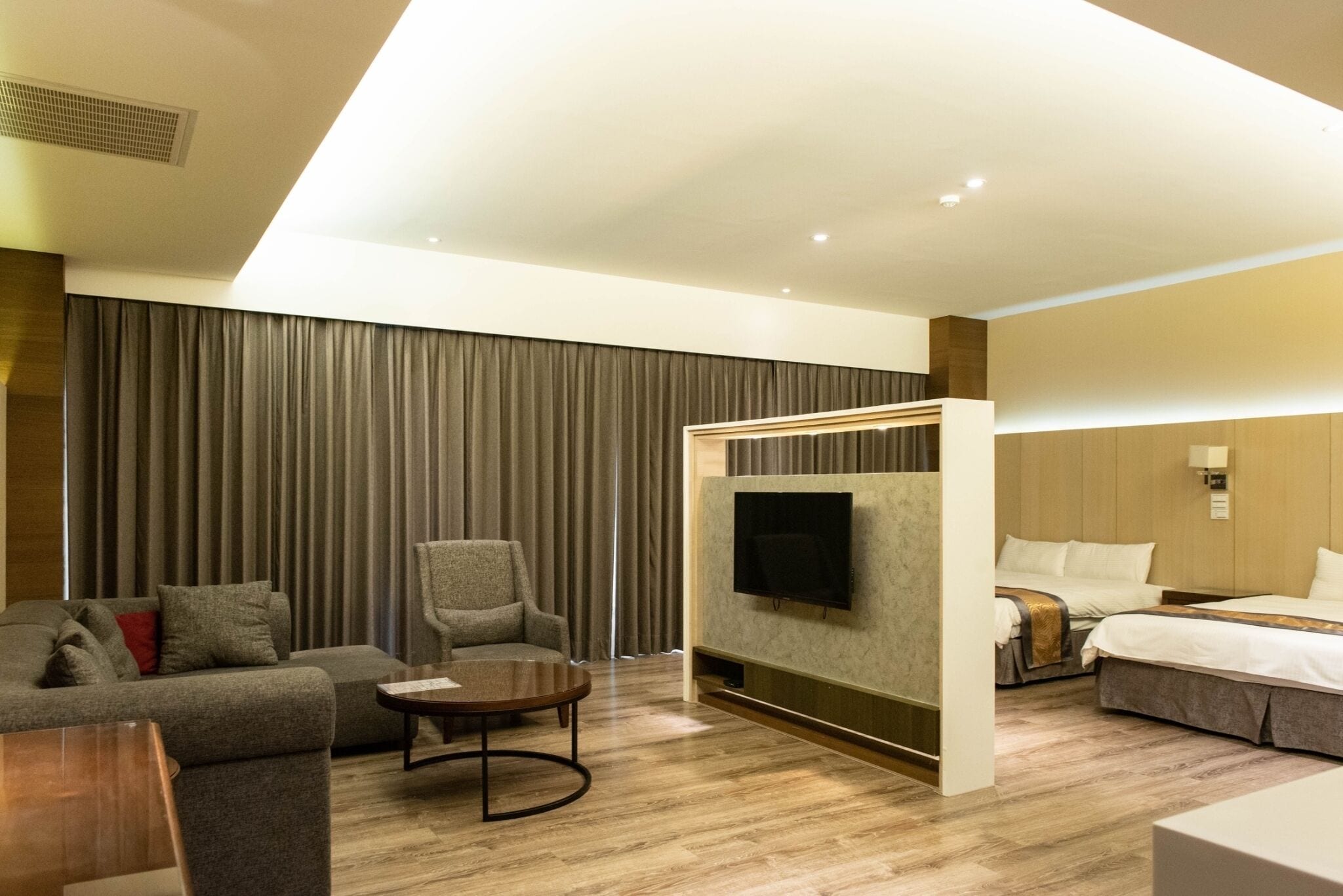 Una habitación de hotel moderna con sofá, sillón, televisión y cama.
