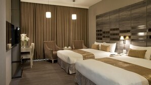Habitación de hotel con dos camas, un escritorio, una silla, un televisor y un mueble de pared grande.