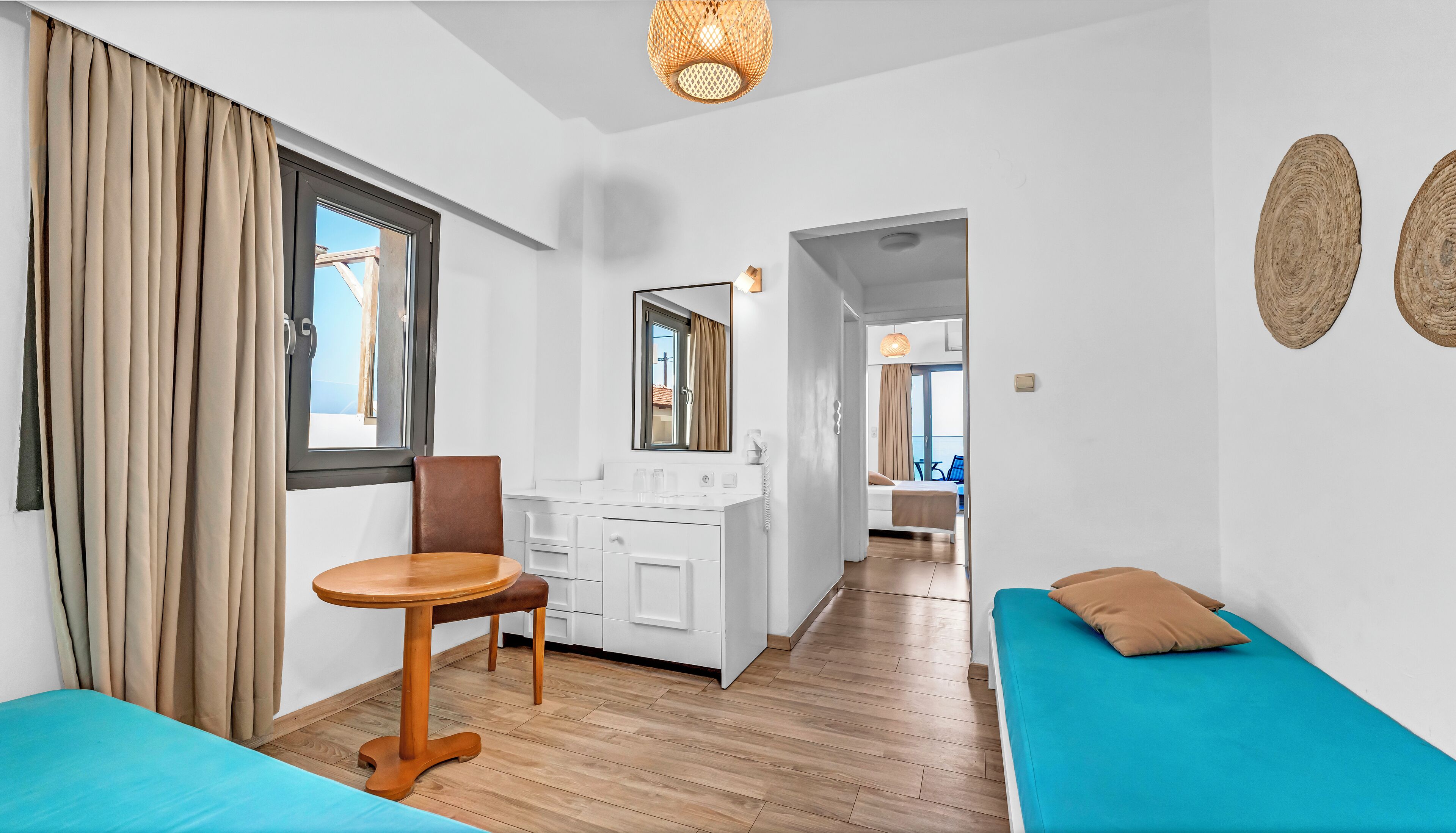 A modern room with a wooden floor, a small wooden table, a brown chair, a white sink, and a bed with a blue mattress.